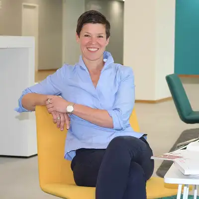 Ruth Schulze von der Robert Bosch GmbH sitzt lächelnd in einem großen Büro mit gelben und grünen Stühlen